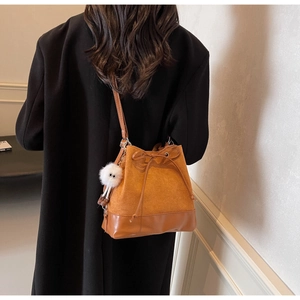 Detail view of brown vintage bucket backpack featuring suede panels and a cute plush charm