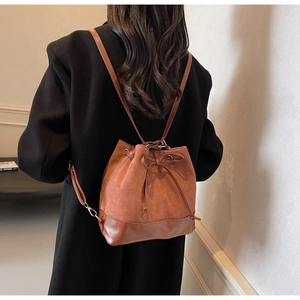 Rear view of brown suede bucket backpack with drawstring and bow detail on a model