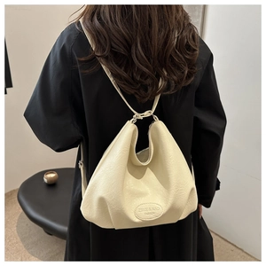 Detail of a beige pleated hobo bag showing the ZSKE & NAG brand logo and slim straps