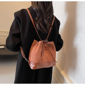 Detail of caramel brown suede bucket backpack with drawstring and bow on black coat