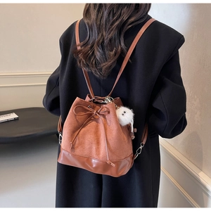 Detail view of brown suede bucket bag with drawstring bow and cute plush toy charm