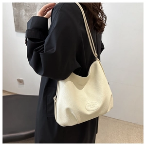 Close-up of creamy white tote bag featuring soft PU leather texture and metal brand tag