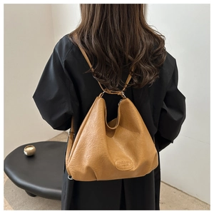 Close-up of caramel leather tote bag with soft pleated texture and embossed logo