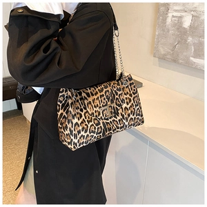Detail of leopard print handbag featuring a gold chain strap and metal T-shaped buckle