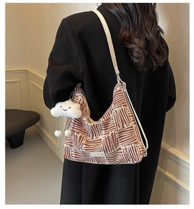Close-up of knit tote bag with brown stripes, fashion label, and cloud pendant charm
