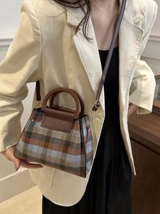 Sac bandoulière vintage à carreaux avec poignées en cuir porté sur blazer blanc