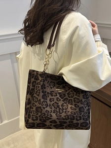 Large leopard print tote bag with leather straps and gold chain worn by a model