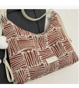 Detail of striped canvas tote bag with fashion label and white fluffy ball pendant