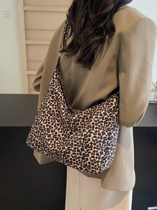 Large leopard print canvas tote bag with wide shoulder strap worn by a female model