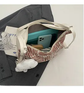 Top view showing the spacious interior of a striped canvas tote bag with a plush charm