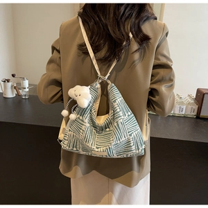 Detail of green striped jacquard hobo bag with plush cloud charm on a shoulder strap