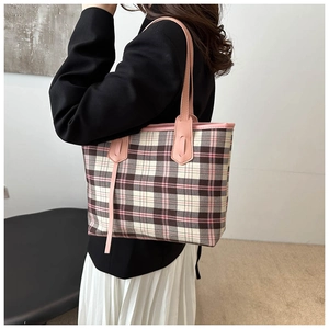 Detail of pink plaid canvas tote bag with leather straps worn by model in minimalist setting