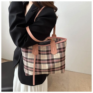 Detail view of retro plaid tote bag with pink leather trim worn by model in suit