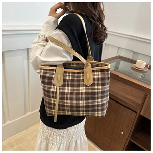 Detail of a large plaid tote bag in British style worn on shoulder for casual commuting