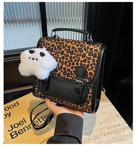 Close-up of leopard print crossbody bag with black leather flap and cute plush charm