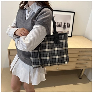 Classic checkered tote bag worn on shoulder by model in a minimalist home setting