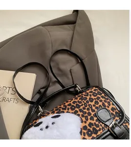 Detail of leopard print shoulder bag featuring a plush panda charm and metal buckle