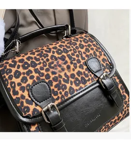 Close-up of leopard print fabric and black leather trim on a stylish crossbody bag