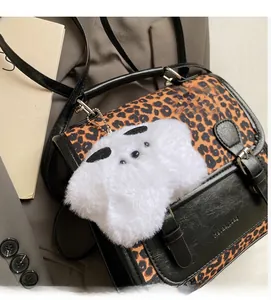 Detail of leopard print tote bag with black leather trim and white fluffy charm