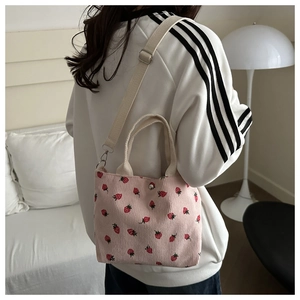 Detailed view of pink corduroy shoulder bag with red strawberry prints and magnet buckle