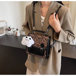 Fashionable leopard print messenger bag worn by a model in a cozy vintage cafe setting