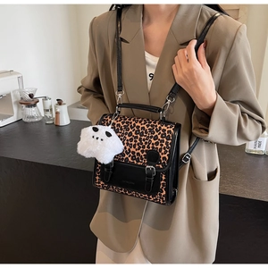 Close-up of leopard print shoulder bag with metal buckles and plush star charm detail