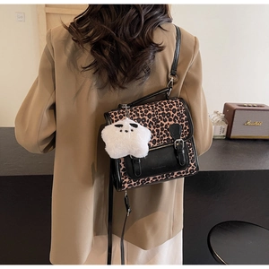 Close-up of leopard print and black leather bag with a plush white star charm