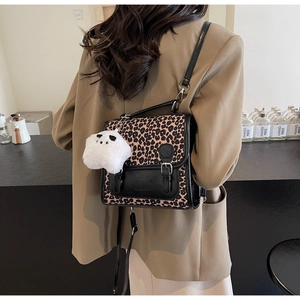 Detail of leopard print crossbody bag with black leather straps and plush bear charm