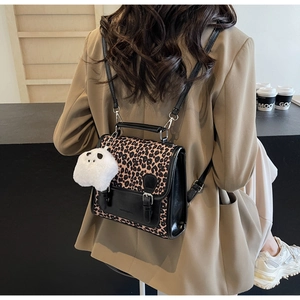 Leopard print backpack with plush ghost charm shown on model in khaki blazer