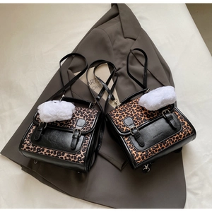 Detail of leopard print patchwork backpack with faux leather straps and fluffy pompom charm