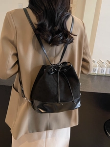 Minimalist black drawstring bucket backpack with a bow detail and leather mix