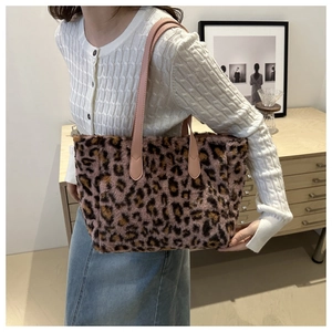 Détail du sac cabas en peluche léopard avec bandoulières en cuir rose porté à l'épaule