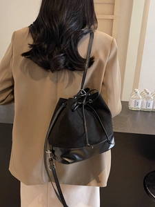 Chic black drawstring bucket bag with suede texture and leather strap for commute