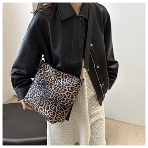 Leopard print canvas tote bag with black strap and gold buckles shown as shoulder bag