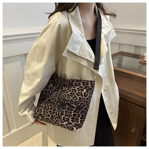 Detail of leopard print tote bag featuring black woven strap and gold metal buckle
