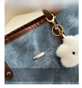 Dettaglio della borsa tote in denim blu con finiture in pelle marrone e charm a nuvola