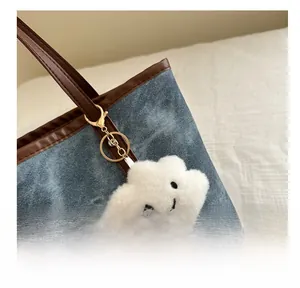 Dettaglio del ciondolo a nuvola bianca con sorriso su una borsa tote di denim