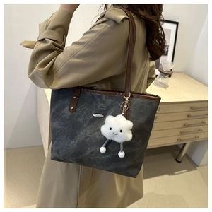 Dettaglio borsa tote grigia lavata con manici in pelle marrone e charm a nuvola bianca