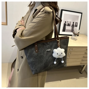 Dettaglio della borsa tote grigia scamosciata con finiture in pelle marrone e ciondolo nuvola