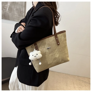 Detail of beige faux suede tote bag with dark brown straps and white cloud charm