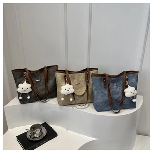 Three minimalist canvas tote bags in grey, khaki and blue with leather straps on a white stand