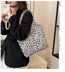 Leopard print canvas tote bag with large capacity shown on model in a stylish indoor setting