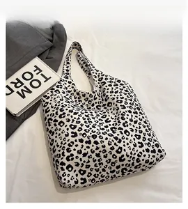 Detailed top view of a large leopard print canvas tote bag on a white textured fabric