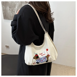 Détail de la broderie teckel sur un sac cabas en velours côtelé crème avec texte