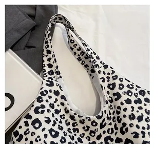 Detail of wide shoulder straps and black and white leopard print canvas tote bag