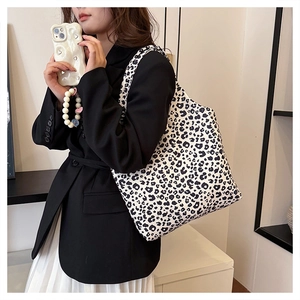 Detail of large leopard print tote bag showing fabric texture and heart charm accent