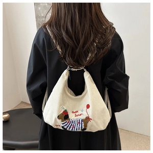 Détail d'une broderie de teckel sur un grand sac cabas en velours porté par un mannequin