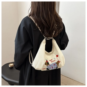 Détail de la broderie teckel sur un sac hobo en velours côtelé blanc cassé porté