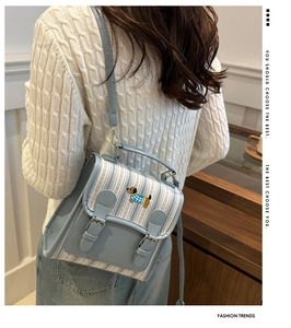 Detail of light blue striped PU backpack featuring delicate dog embroidery and handle