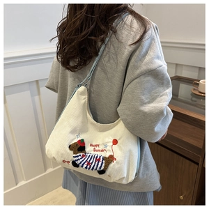Détail de la broderie teckel sur un sac en velours côtelé blanc avec bandoulière